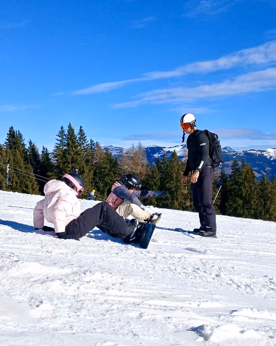 WOW-coach geeft snowboardles aan twee leerlingen op de piste